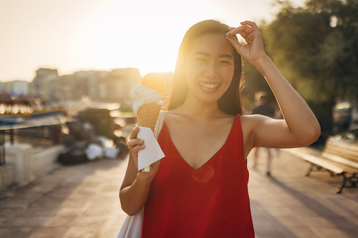 Portrait of a smiling Asian woman eating ice cream and looking directly at the camera