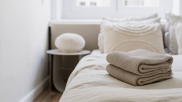 Stack of clean folded bath towels on comfort bed in cozy hotel room