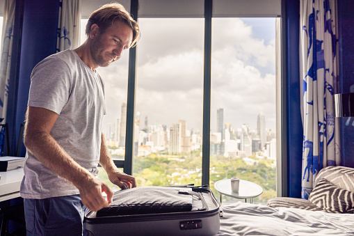 He unpack his carry on luggage on the bed, taking out his belongings