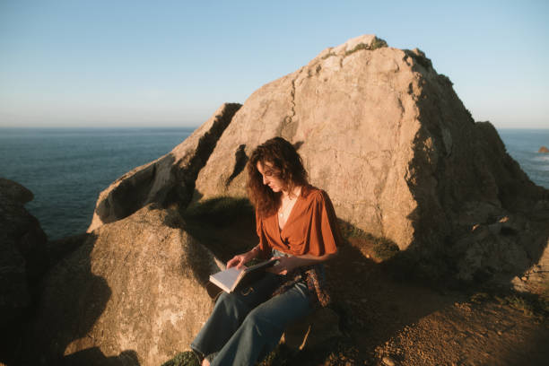 istock Woman reading by the sea 2093647514