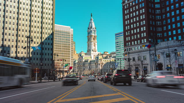 Time lapse of Philadelphia's landmark historic City Hall with traffic car and crowd pedestrian tourist crossroad city street in Philadelphia, Pennsylvania, United States
