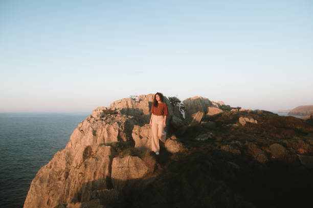 Porttrait of a young woman leaning on a rock at sunset