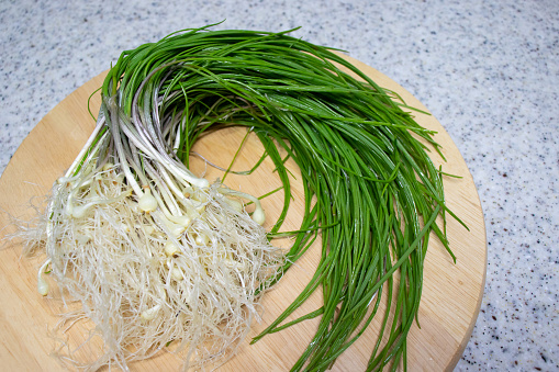 Fresh Wild Chive vegetables on a round wooden tray.