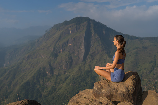 Young woman on top of mountain in lotus position