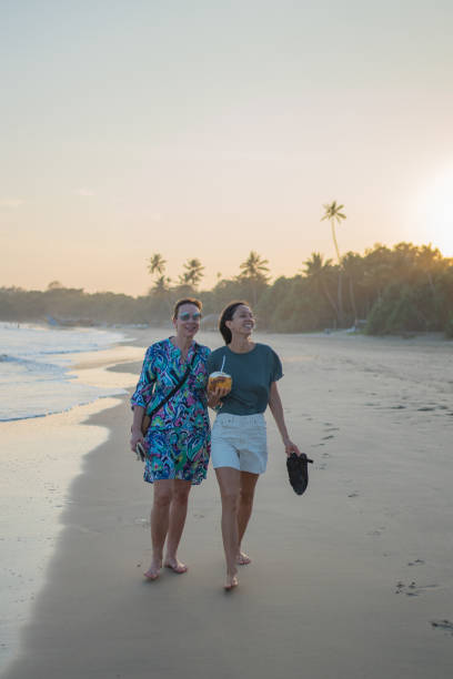 istock Mother and daughter walk down beach together 2093727950