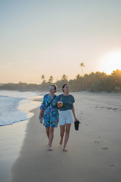 Mother and daughter walk down beach together