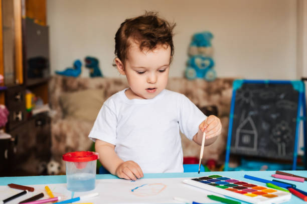 istock a small boy sits on a chair and draws with colored paints 2093732172