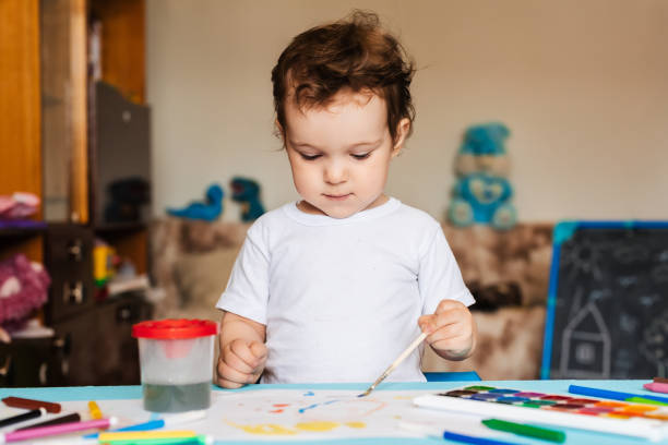 istock Happy cheerful child draws with a brush in an album using multi-colored paints 2093732691