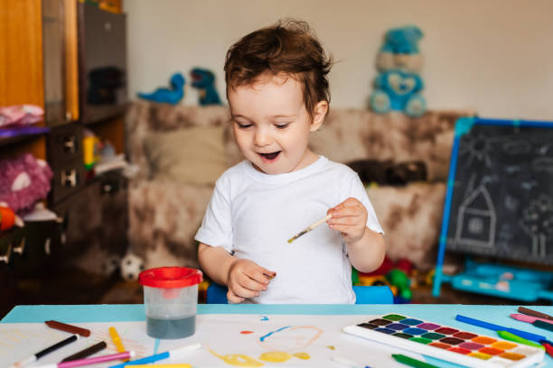 istock Happy cheerful child draws with a brush in an album using multi-colored paints 2093732693