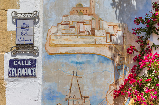 Street sign, mural and pink flowers in the historic town of Altea, Spain
