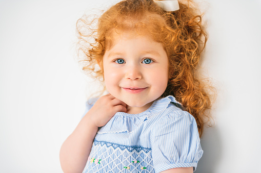 A Little cute girl in a dress with redhead. The child is 2 years old.