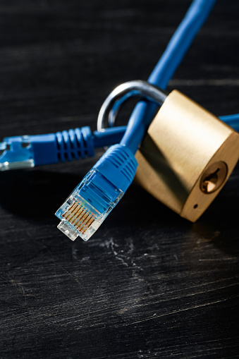 Network cable and padlock on dark background