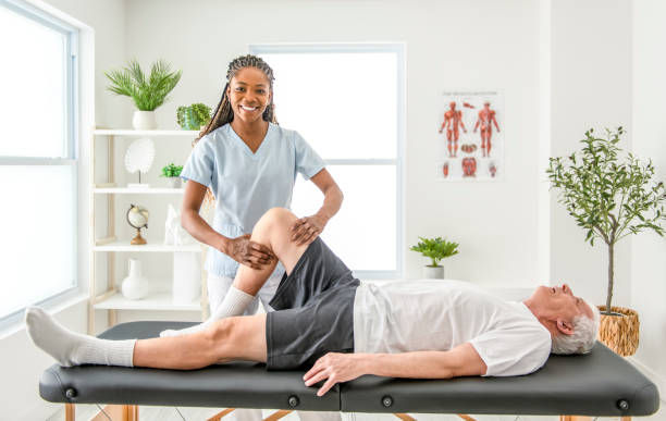 Black physiotherapist helping senior man with in clinic. Elderly man undergoing physiotherapy treatment for injury A black Physiotherapist helping senior man with in clinic. Elderly man undergoing physiotherapy treatment for injury chiropractors stock pictures, royalty-free photos & images