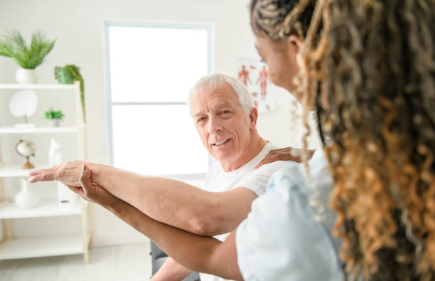 istock Black physiotherapist helping senior man with in clinic. Elderly man undergoing physiotherapy treatment for injury 2093763475