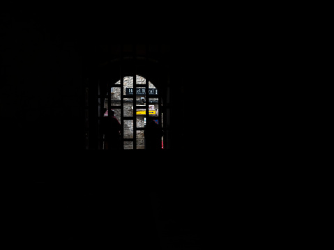 A middle-aged man leaning against the church door is seen from inside the church.