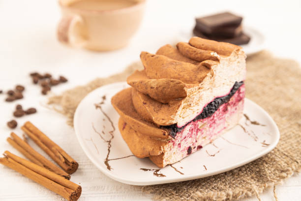 Zephyr or marshmallow cake with cup of coffee on white wooden background and linen textile. side view, close up, selective focus.