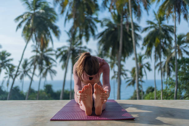 Young woman performs yoga in tropical setting