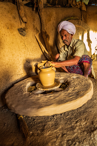 Indian potter working in his workshop, desert village in Rajasthan, India