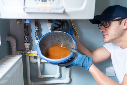 Man Looking At Water Leaking From Broken Natural Gas Combi Boiler