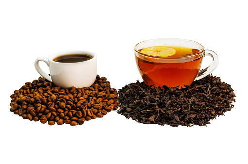 A cup of coffee stands on coffee beans and a cup of tea on loose tea, isolated background