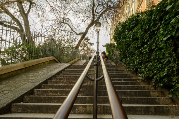 Paris, France - February 17, 2024 : View of tourists walking up and down the picturesque staircases with the lanterns in the Montmartre area in Paris France