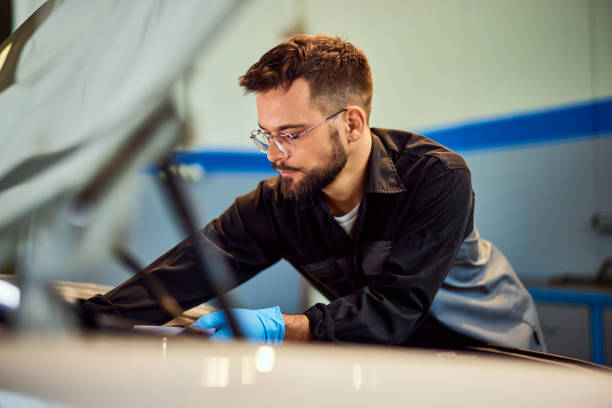 istock Mechanic man fixing a car, dressed in a uniform, in his garage. 2093794423