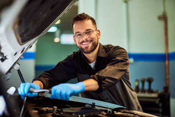 istock A portrait of a mechanic man smiling for the camera while working on a car, using some tools. 2093794429