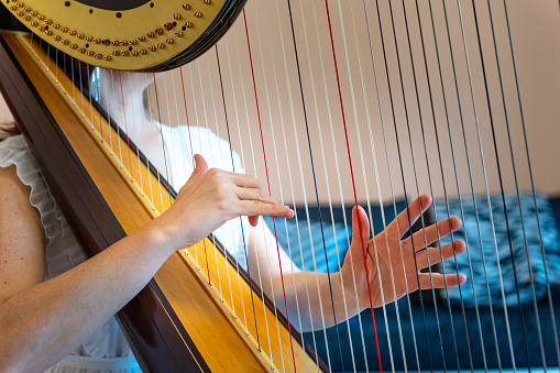 Woman play the harp during a symphonic concert. Close up on hands and strings.