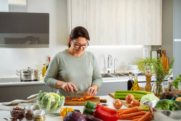 istock Woman slicing fresh organic carrots on kitchen counter 2093870722
