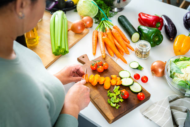 istock Woman slicing fresh organic carrots on kitchen counter 2093871265
