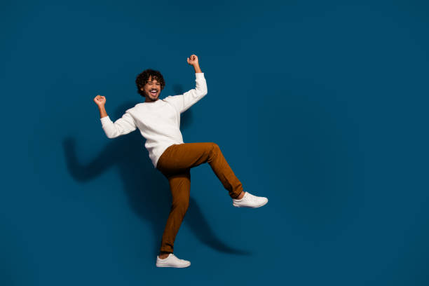 istock Full length photo of excited lucky guy dressed white pullover rising fists walking empty space isolated dark blue color background 2093886505