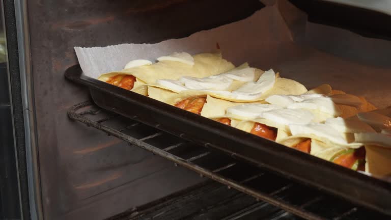 Male hands placing prepared homemade mexican enchiladas into oven