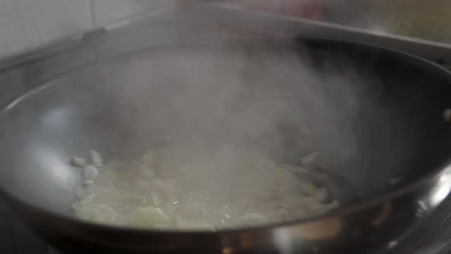 Chopped onions are fried in a pan in vegetable oil, stirring occasionally. Close-up