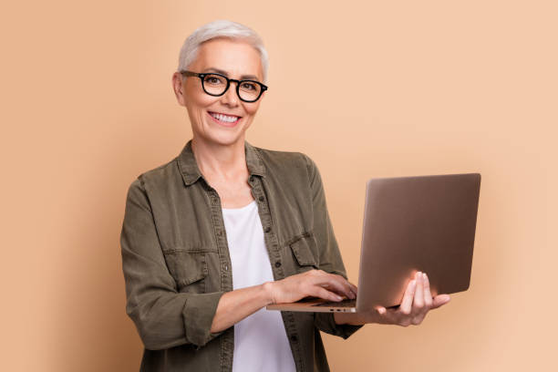 istock Photo of it specialist mature age woman strong middle level python developer using laptop linux isolated on beige color background 2093894910