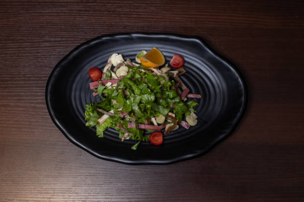 istock A black plate with a salad on it 2093908074