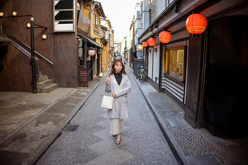 Female tourist walking on traditional Japanese narrow street in Kyoto