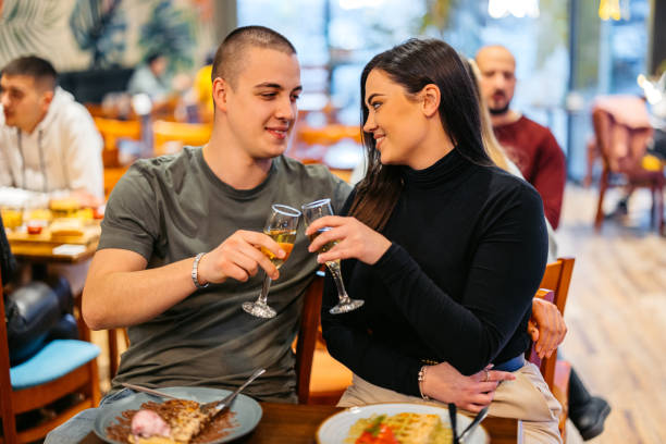 young couple cheering with champagne while eating belgian waffles in a pub - waffle eating meal food and drink zdjęcia i obrazy z banku zdjęć