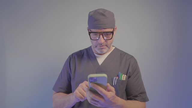 Portrait of a doctor using a smartphone on blue background.