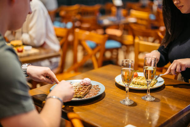 young couple eating belgian waffles and drinking champagne in a pub - waffle eating meal food and drink zdjęcia i obrazy z banku zdjęć