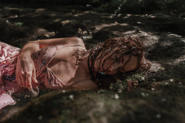 Medium shot portrait of a woman with wet hair, closed eyes and pink dress relaxing in the river.