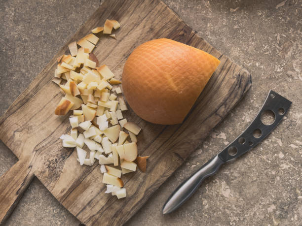 Slicing and chopping smoked caciocavallo cheese on a wooden board