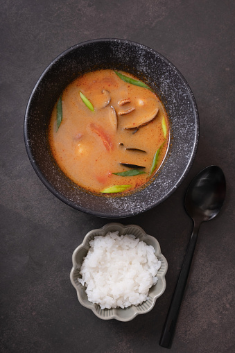 Tom yum soup and rice on dark background top view.