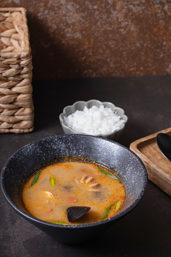 Tom yum soup and rice on a gray background angle view. on dark background.