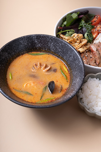 Tom yam soup and bowl with rice, veal and vegetables and angle view vertical format