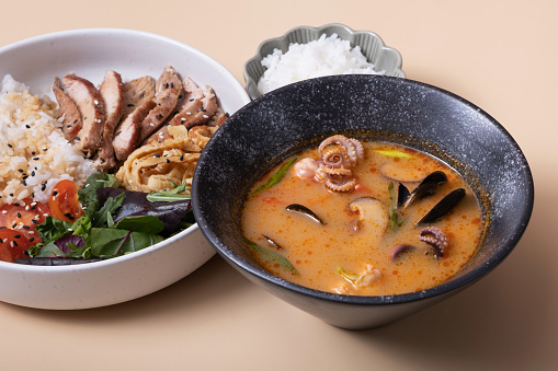 Tom yam soup and bowl with rice, veal and vegetables angle view