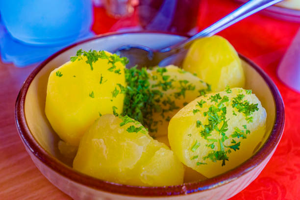 Colorful photo of a bowl of cooked potatoes garnished with parsley.