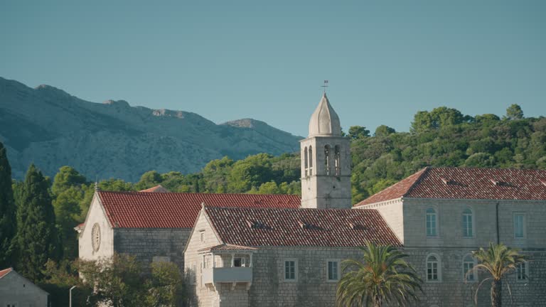 Franciscan monastery with Mediterranean architecture and red rooftop on an island. Close-up shot of monastery bell tower.