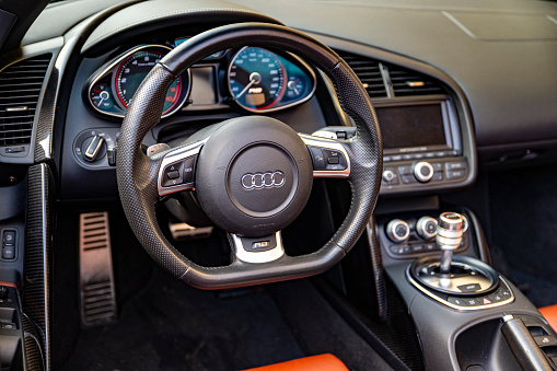 Audi R8 V10 Plus sports car dashboard. The Audi R8 is a mid-engine, two-seater sports car manufactured and marketed by the German automobile manufacturer Audi. The Audi R8 V10 Plus is a high-performance variant of the Audi R8 sports car.