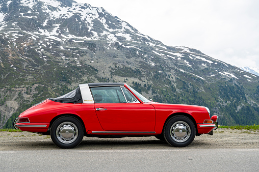 Porsche 912 Targa classic sports car parked alongside and alpine road high up in the Tyroler Alps in Austria. The Porsche 912 Targa is a classic sports car produced by Porsche AG from 1965 to 1969. The Targa variant of the 912 was introduced in 1966 and was known for its distinctive open-top design with a rollbar and removable top and rear section of the roof.