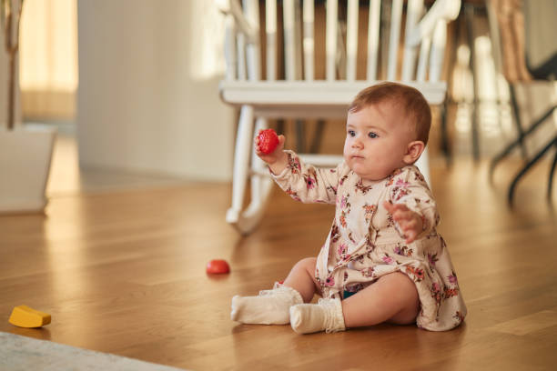 Toddler baby girl playing with plastic ball at home